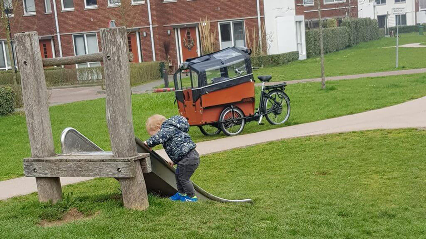 Bakfiets met kind in speeltuin